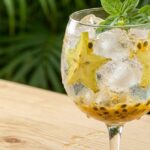 Taça de gin tônica com carambola, maracujá e manjericão