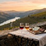 Duas taças de vinho do Porto com queijo azul e nozes em varanda com vista para vinhedos